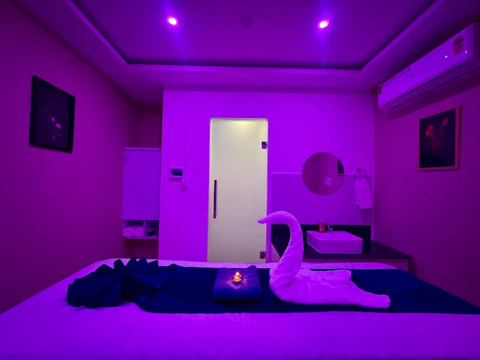 Massage table with folded towels in a purple-lit room at Sky Days Spa